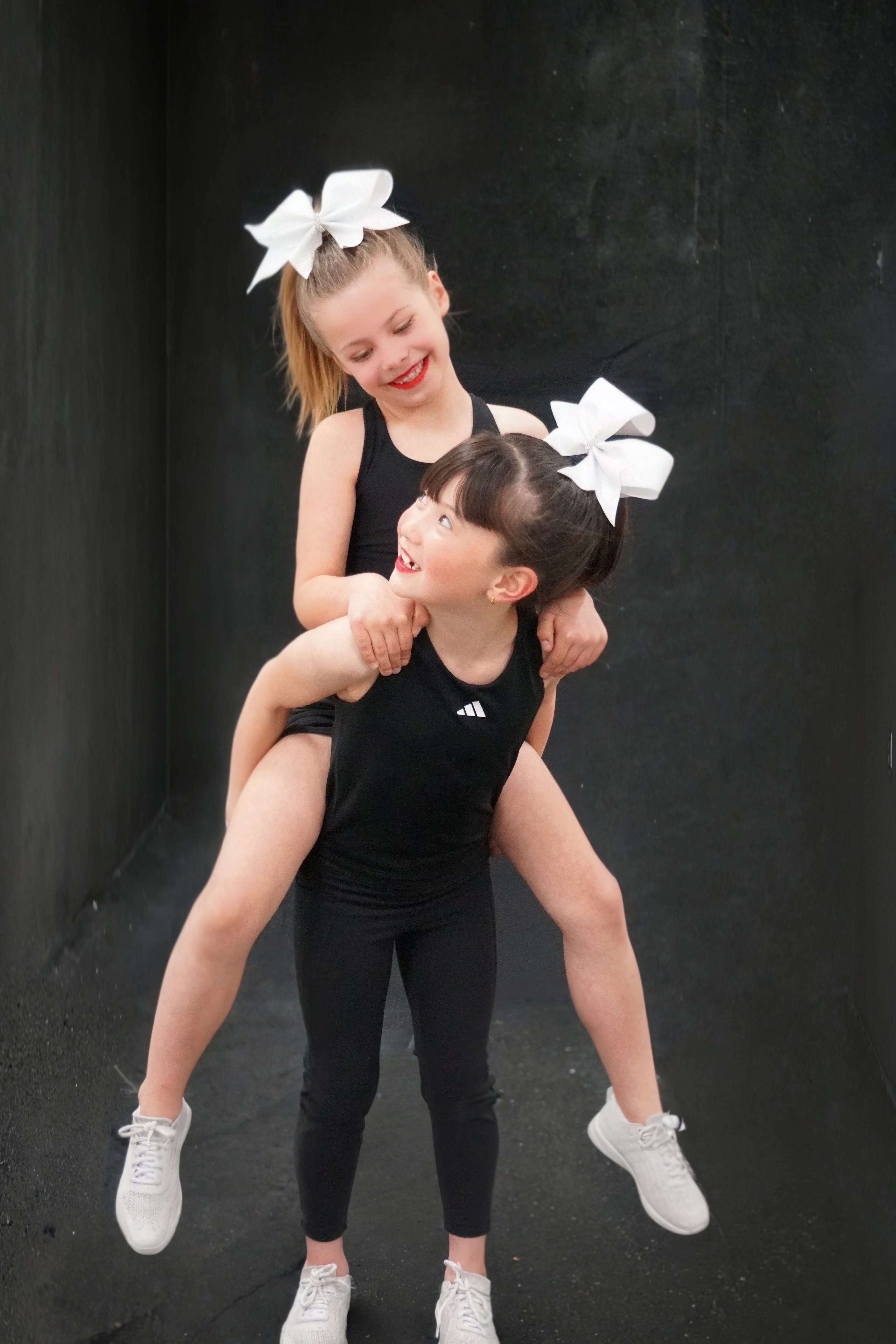 Two students in black athletic wear with white bows