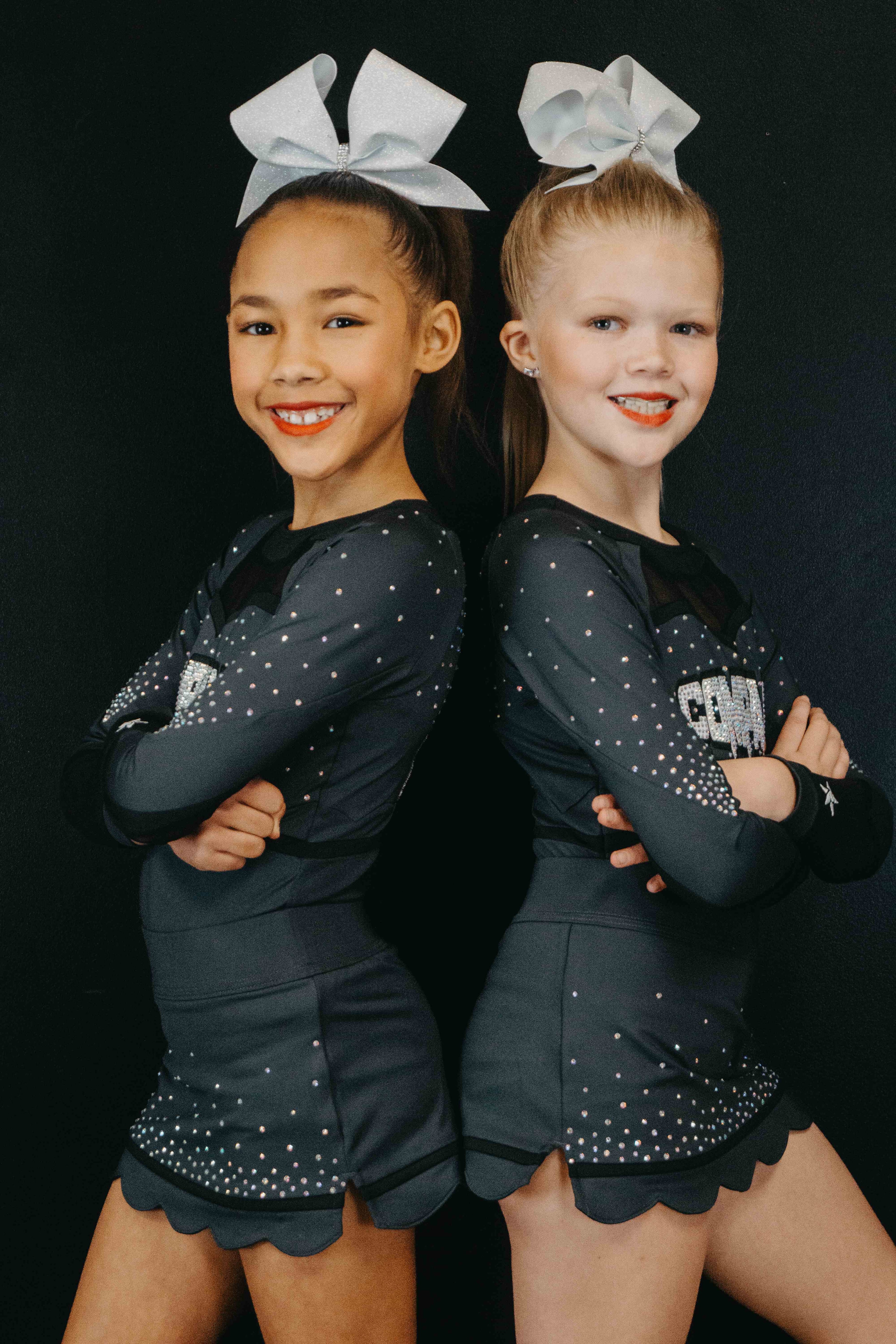 Two students posing back to back in cheer uniforms
