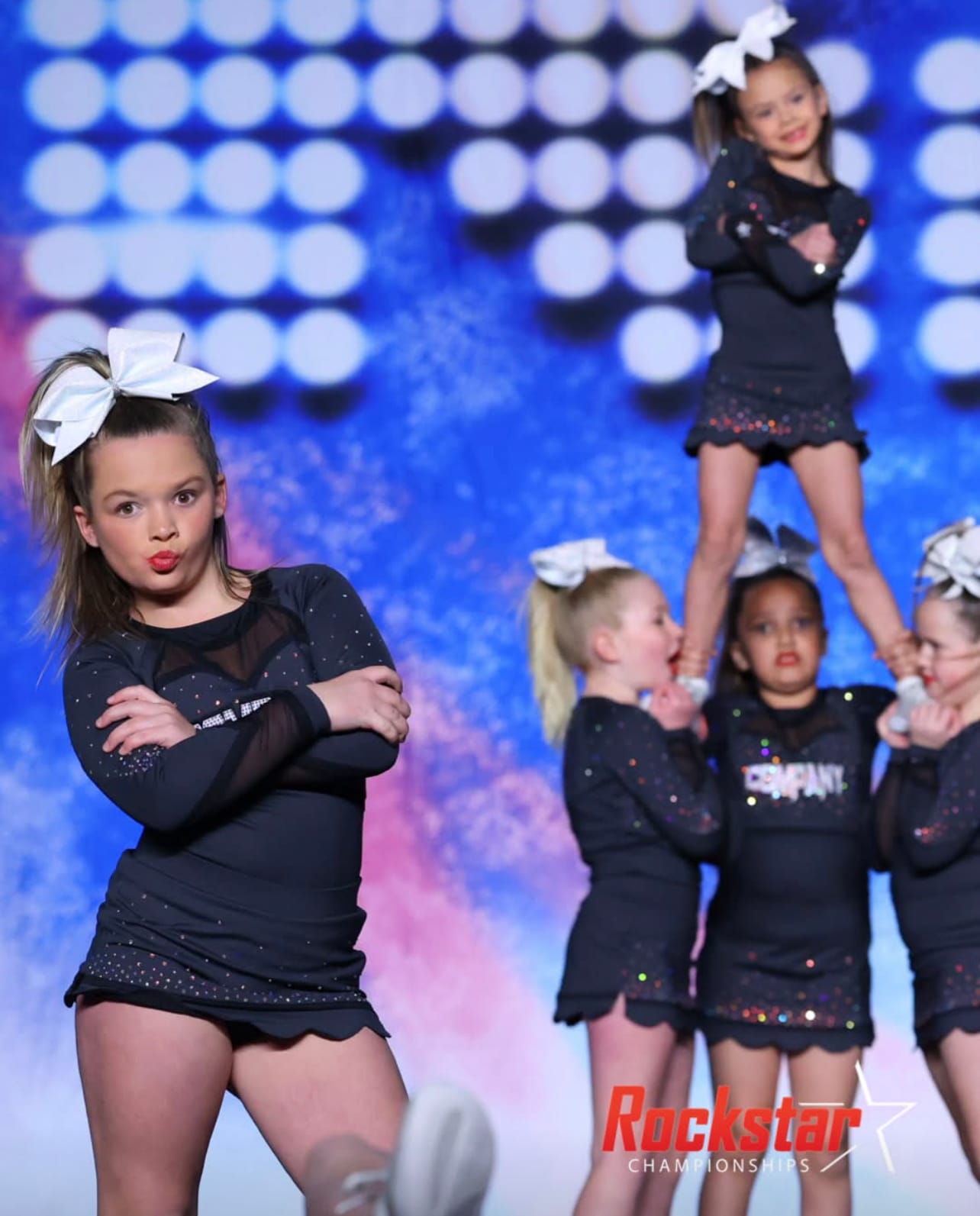 Group of dancers in matching black outfits performing on stage